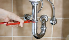 Plumber removing pipes under a sink to clean out the drain pipes